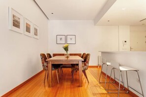 A dining area with a wooden table and chairs, a vase with flowers, and framed pictures on the wall. - NOA - Süngü 1 (Istanbul)