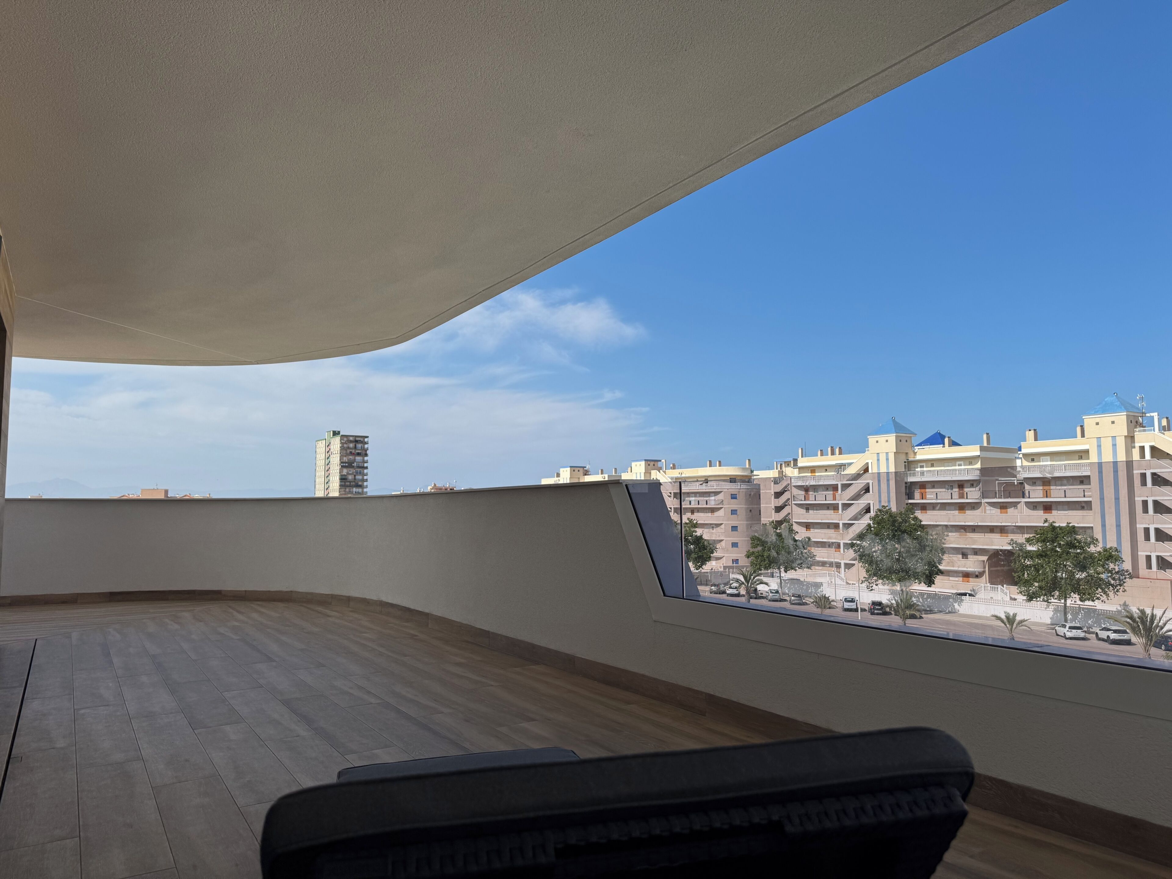 A room with a view of a cityscape, a curved ceiling, and a window overlooking a parking area.