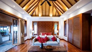 A spacious living area with a wooden ceiling, a sofa with red cushions, and a coffee table. - Villa ZeniMo, Surin Beach, pool, 9 BR 18 guests (Phuket)