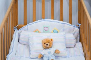 A crib with a teddy bear, striped bedding, and a pillow with a heart design. - Villa ZeniMo, Surin Beach, pool, 9 BR 18 guests (Phuket)