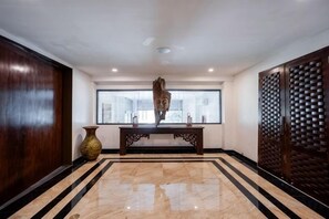 A lobby with a marble floor, a wooden reception desk, a large vase, and a decorative screen. - Villa ZeniMo, Surin Beach, pool, 9 BR 18 guests (Phuket)