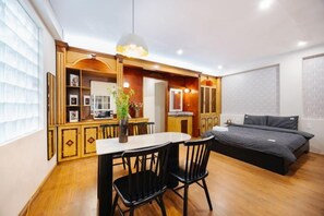 A compact room with a dining table, chairs, a bed, and a large window. - VietHOME - 22 Pho Hue - Apartment 301 (Hanoi)