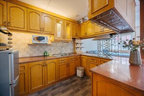 Una cocina con armarios de madera, un refrigerador de acero inoxidable, un microondas y un fregadero.