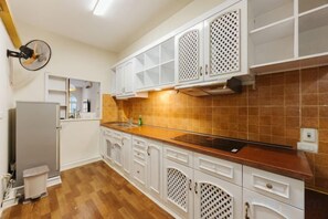 A kitchen with white cabinets, a wooden countertop, and a tiled backsplash. - VietHOME - 22 Pho Hue - Apartment 301 (Hanoi)
