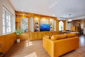 A spacious living room with a large sofa, wooden cabinetry, and a television. - VietHOME - 22 Pho Hue - Apartment 301 (Hanoi)