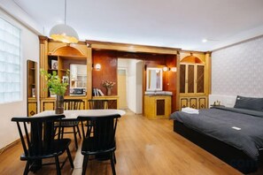 A compact hotel room with a dining area, a bed, and a kitchenette. - VietHOME - 22 Pho Hue - Apartment 301 (Hanoi)