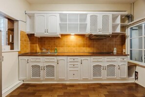A kitchen with white cabinets, a tiled backsplash, and a wooden floor. - VietHOME - 22 Pho Hue - Apartment 301 (Hanoi)