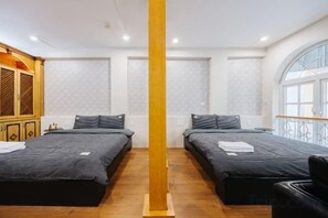 A hotel room with two beds, a wooden column, and a large window. - VietHOME - 22 Pho Hue - Apartment 301 (Hanoi)