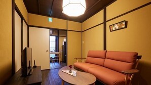 Ein Zimmer mit einer Couch, einem kleinen Tisch und einem Fernseher.