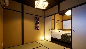 Ein traditioneller japanischer Raum mit Tatami-Böden, einem Bett mit kariertem Überwurf und einer Wand-Klimaanlage.