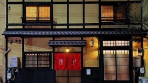 Ein traditionelles japanisches Gebäude mit zweistöckiger Bauweise, einem Ziegeldach und einem roten Eingangstor.