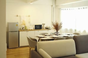 Cocina compacta con refrigerador, microondas y comedor con mesa y sillas.