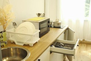 Una cocina con microondas, escurreplatos y fregadero.