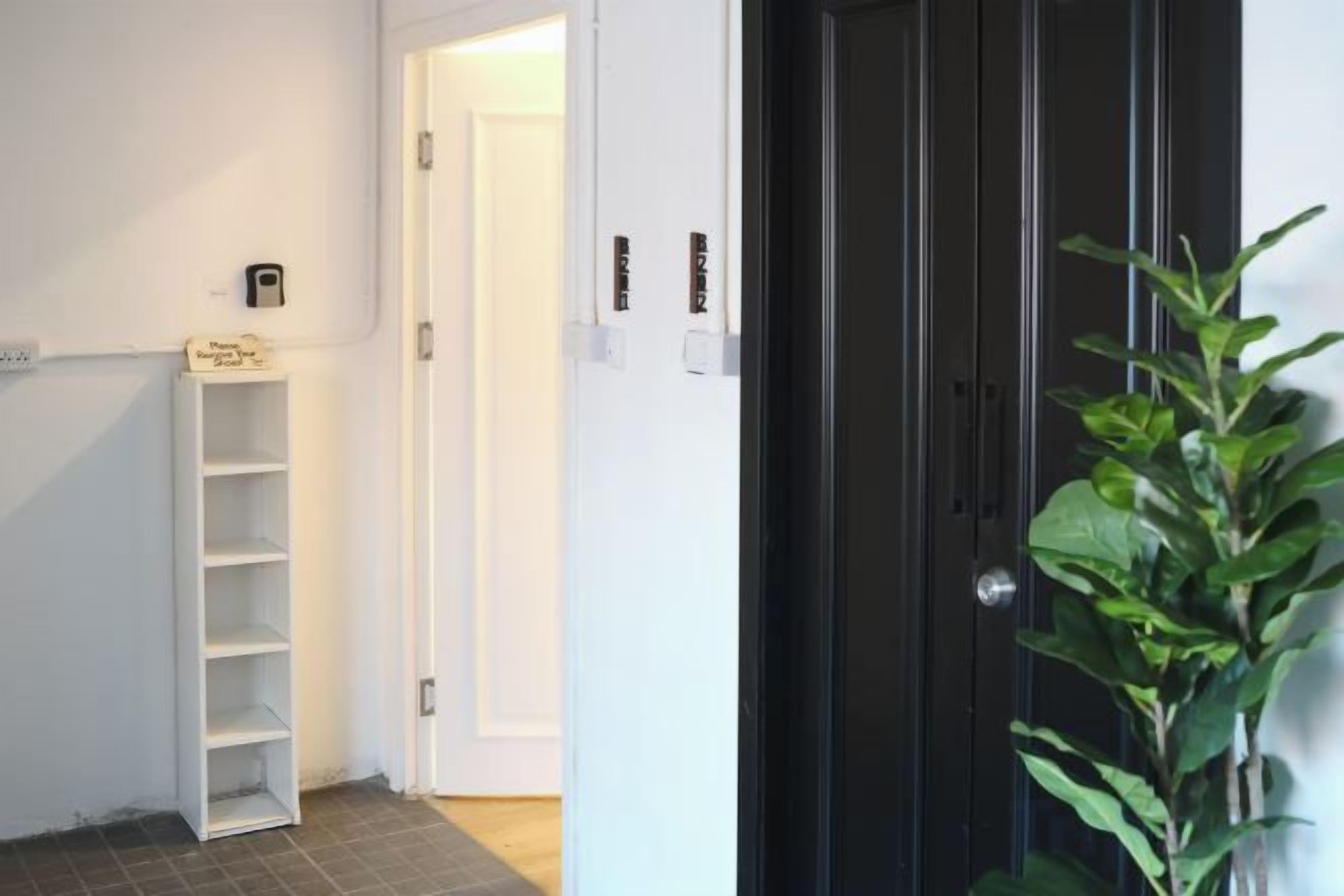 A hallway with a white shelving unit, a black door, and a potted plant.