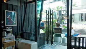 A hotel entrance with a glass door, a bench, a radiator, a framed picture, and a sign indicating the door is closed. - Baanpoon Apartment (Koh Samui)
