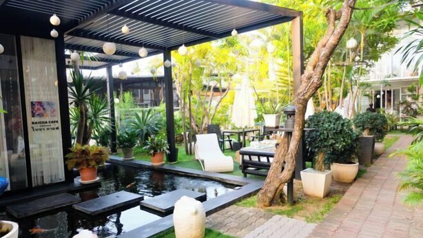 A modern outdoor seating area with a pool, potted plants, and a pergola. - Baanpoon Apartment (Koh Samui)