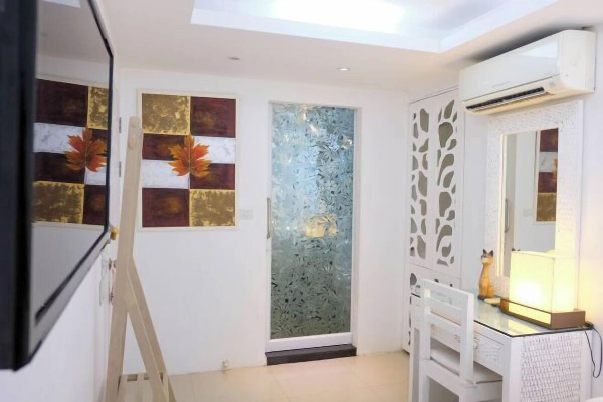 A bathroom with a white vanity, a mirror, and an air conditioning unit.