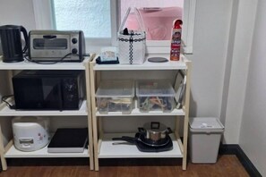 A kitchenette with a microwave, toaster, kettle, and a small trash bin. - My Sukhumvit Villa (Bangkok)