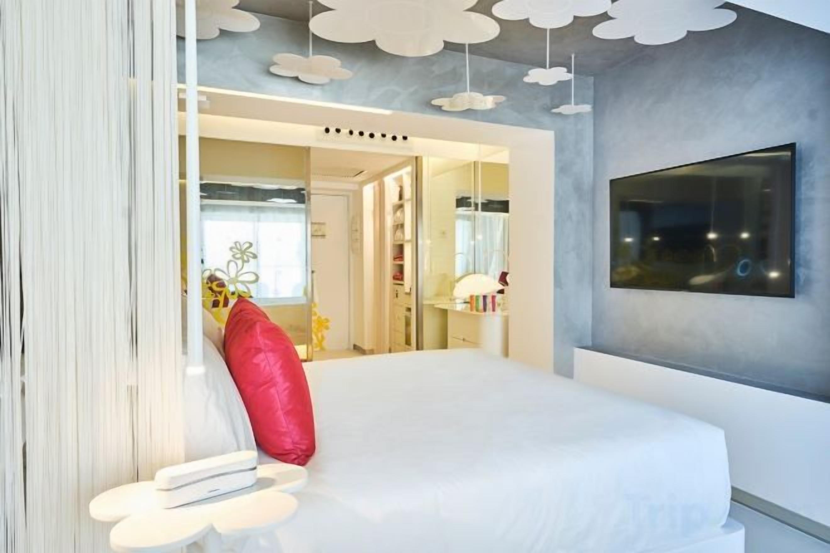 Ein Schlafzimmer mit einem Bett, einem Spiegel und einem an der Wand befestigten Fernseher.