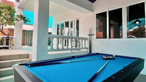 A pool table with a blue felt surface, a pool cue, and a set of balls.