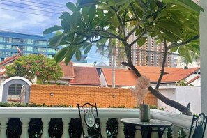 A balcony with a view of a building with a red-tiled roof, a brick wall, and a tree. - Chasing Light Villa (Pattaya)