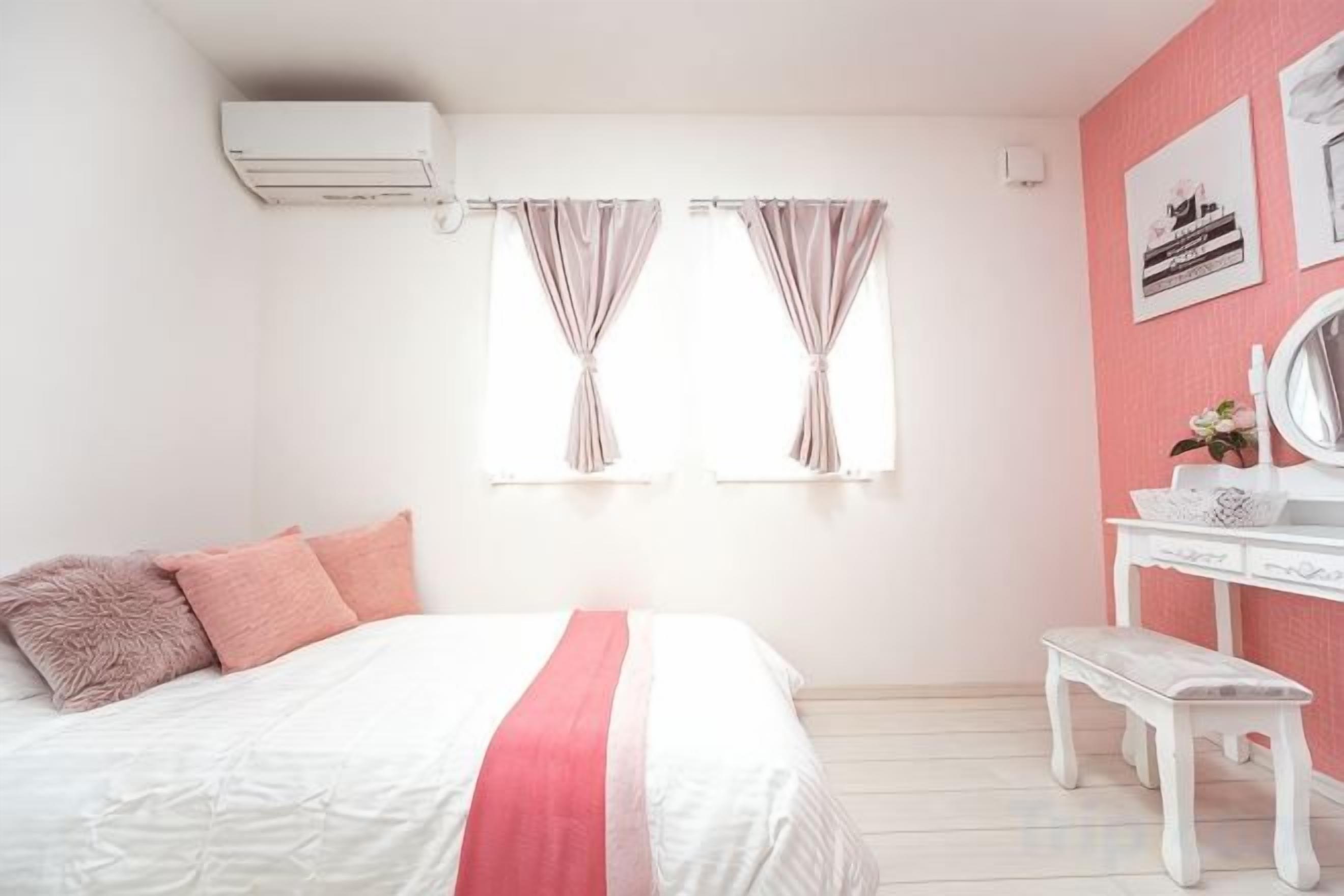 A bedroom with a bed, a vanity, and two windows with curtains.