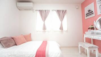 A bedroom with a bed, a vanity, and two windows with curtains.