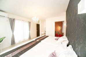 A hotel room with a large bed, a desk, and a chair. There is a window with curtains, a chandelier, and a door leading to another room. - Shiga Lakeside Villa (Takashima)