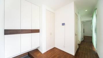 Een gang met houten vloer, witte muren en een deur naar een andere kamer.