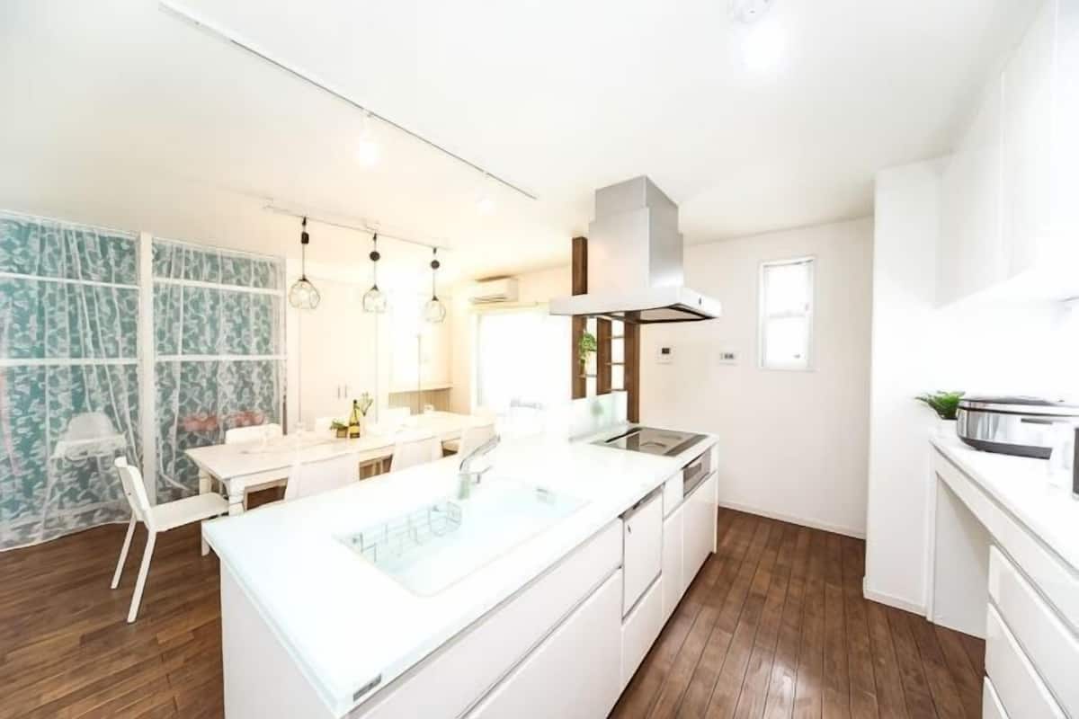 Une cuisine moderne avec des meubles blancs, un grand îlot central et des luminaires suspendus.