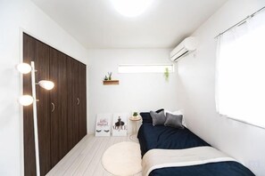 A compact bedroom with a bed, bedside table, and a wardrobe. - Shiga Lakeside Villa (Takashima)