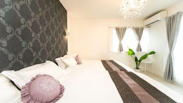 Ein Hotelzimmer mit einem großen Bett, einer Kandelaber, einem Vorhangfenster und einer Pflanze.