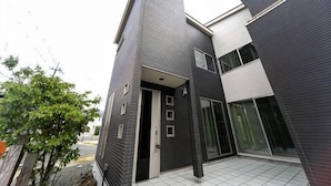 A modern two-story building with a dark exterior, a visible entrance, and a tiled floor. - Shiga Lakeside Villa (Takashima)