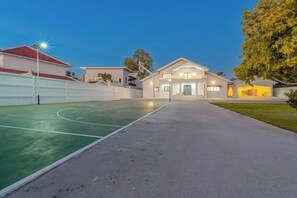 Il s’agit d’une propriété résidentielle dotée d’un terrain de basketball, d’une allée et d’une maison avec un toit rouge.