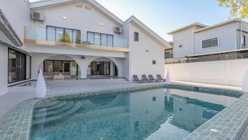 Uma casa moderna com piscina, varanda e área de estar coberta.