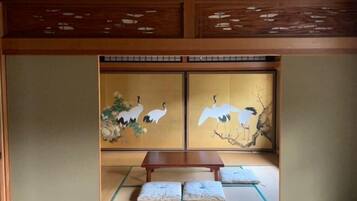 A traditional Japanese room with tatami flooring, a low wooden table, and sliding doors with crane paintings.