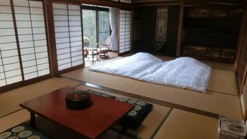 A traditional Japanese room with tatami flooring, a futon bed, a low wooden table, and sliding doors.