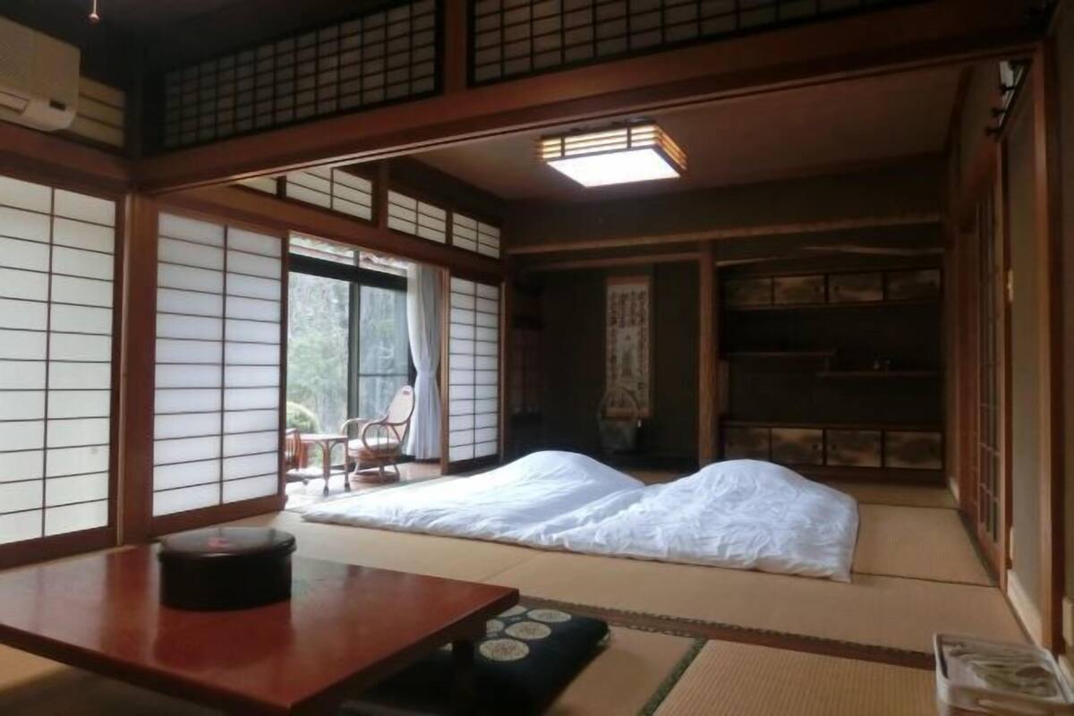 A traditional Japanese room with tatami flooring, a low wooden table, and a futon bed.