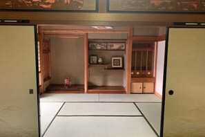 Ein traditioneller japanischer Raum mit Tatami-Bodenbelag, einer Shoji-Schiebetür und einem kleinen Schrein mit einer Statue.
