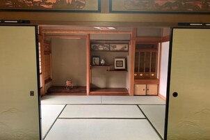 Una habitación tradicional japonesa con suelo de tatami, puerta corredera de shoji y un pequeño santuario con una estatua.