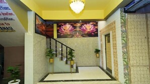 Un vestíbulo con una escalera, una araña y un mural con flores de loto.