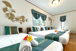 A hotel room with four beds, each with a white and green bedspread, and decorative wall art. - Papillon (Motobu)