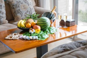 A wooden table with a fruit bowl, a bottle of champagne, and two glasses. - Papillon (Motobu)