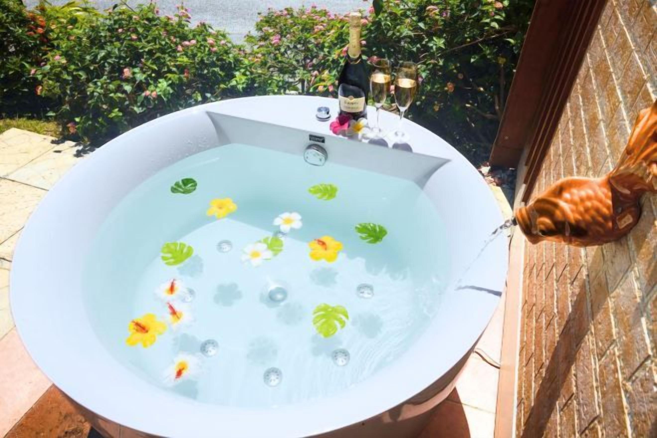 A hot tub with flowers and a bottle of champagne.