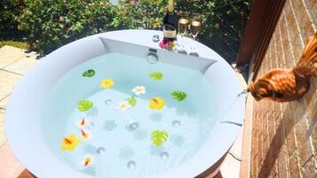 A hot tub with flowers and a bottle of champagne.