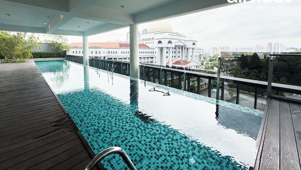 Ein Infinity-Pool auf dem Dach mit freiem Blick auf eine Stadtlandschaft und ein großes Gebäude im Hintergrund.