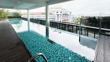 A rooftop infinity pool with a clear view of a cityscape and a large building in the background.