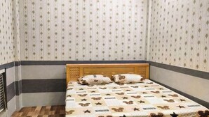 A small, neatly arranged room with a bed, a wooden headboard, and a patterned wall. - Chill Out (Vy Da)
