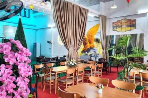 Un ristorante con diversi tavoli e sedie, un grande murale sulla parete e piante in vaso.
