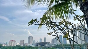 A cityscape with high-rise buildings, a bridge, and palm trees. - Paragon Suites L18 By UCome Homestay (Johor Bahru)